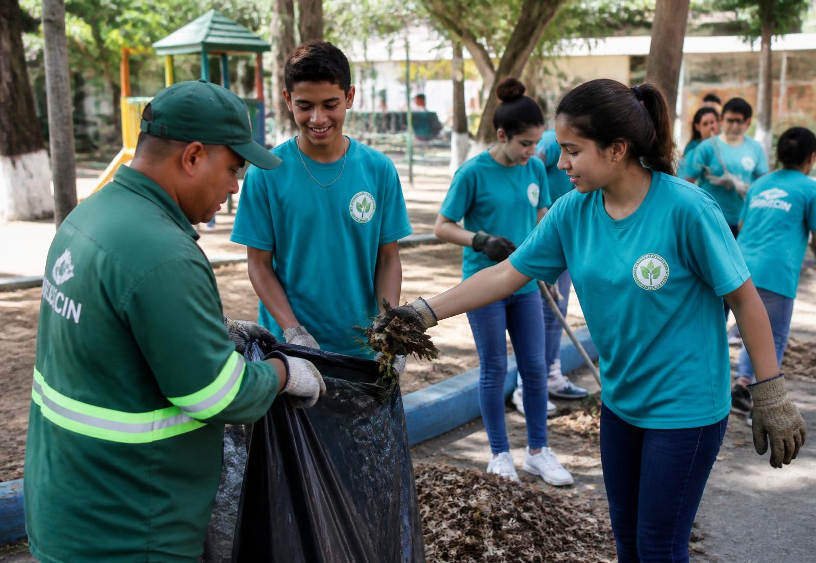 Teenagers and municipal workers cleaning a neighbourhood park in El Salvador