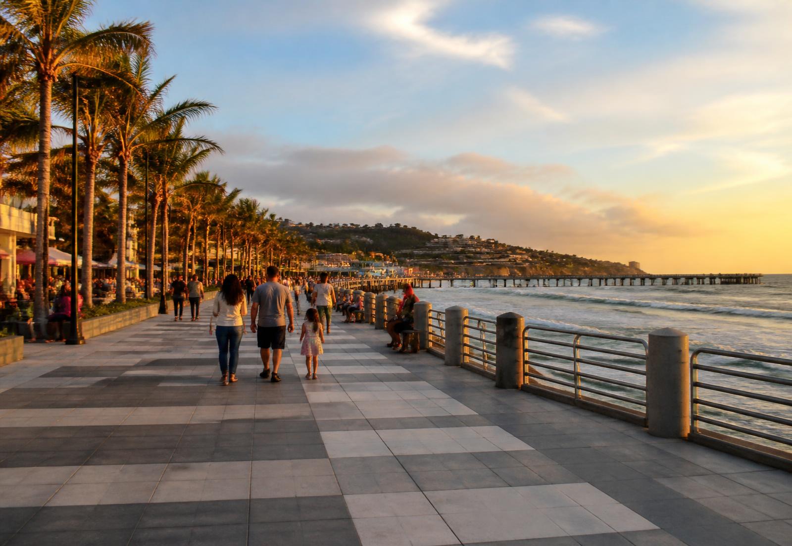 The renovated Puerto de La Libertad boardwalk at golden hour with families walking along the promenade