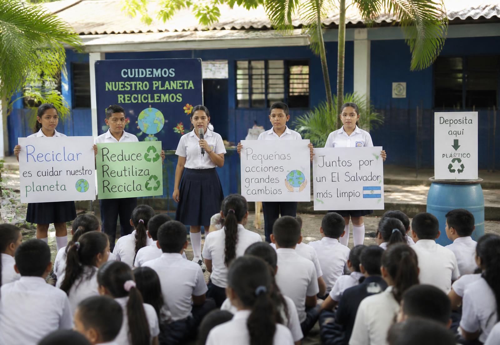 Salvadoran students leading a recycling assembly in their schoolyard with handmade signs