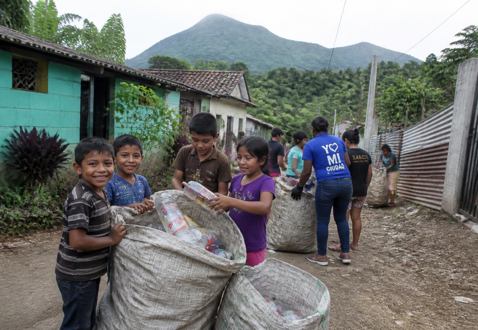 Children in a rural Salvadoran village filling sacks with plastic bottles for recycling